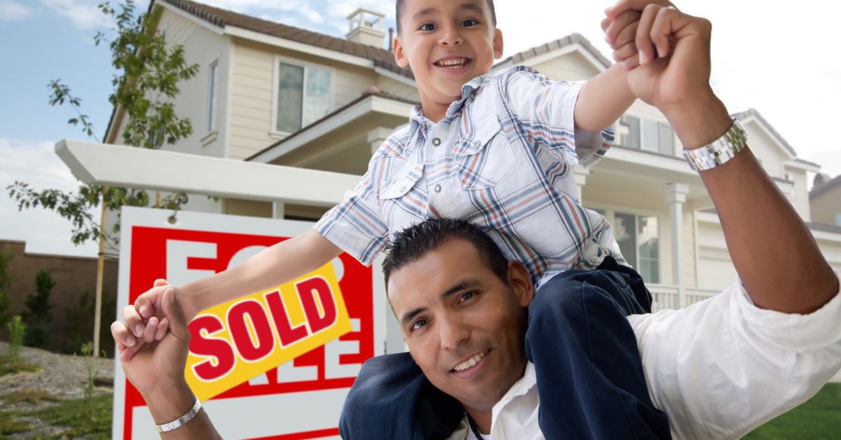 Father and Son with Sold Sign in Background